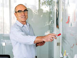 De leraar wijst naar het whiteboard.